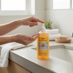 Bienenprodukte Shop API honey soap with orange oil in a pump bottle being dispensed into hands in a bright bathroom.