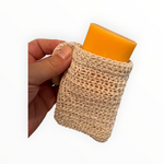 Bienenprodukte Shop Seifensäckchen aus beigem Baumwollnetz mit einem gelben Seifenstück in der Hand gehalten